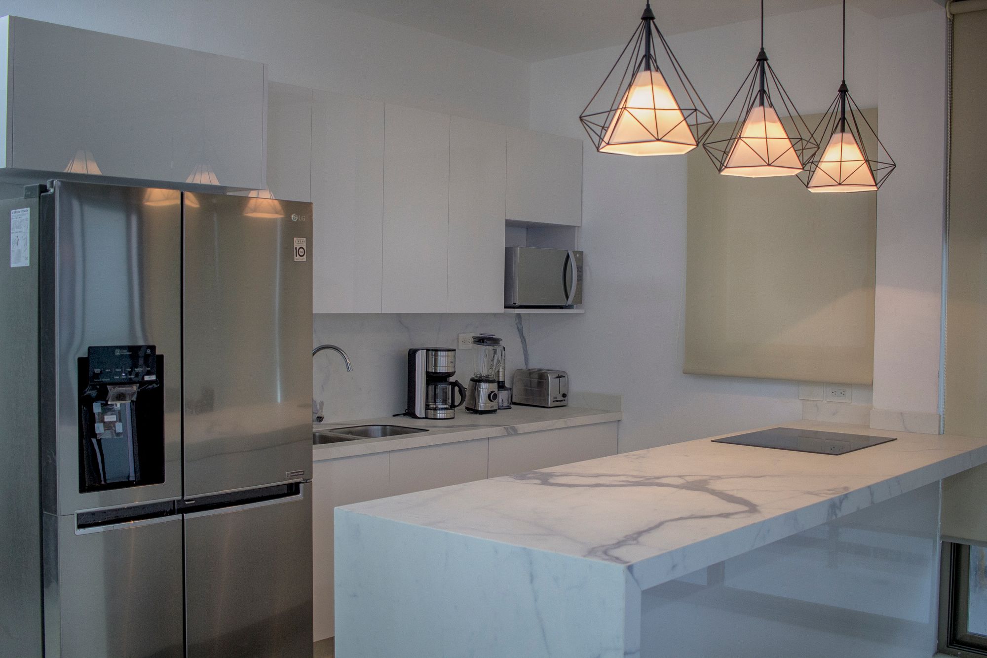 Modern home kitchen with pendant lighting over a marble island